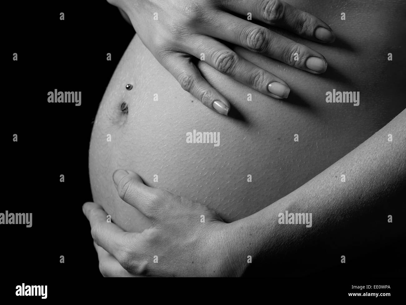 A woman holds her hands on her stomach or bump whilst pregnant. Stock Photo