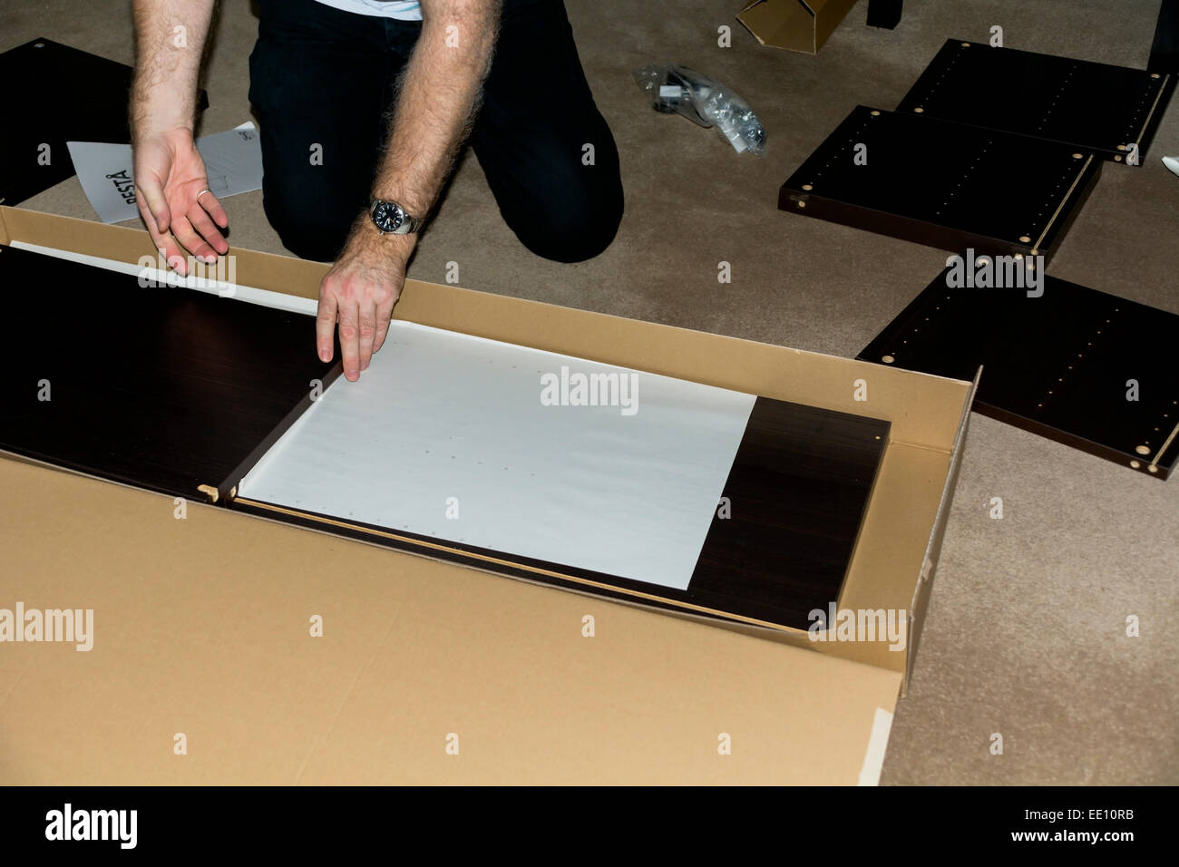 This man is assembling flat-packed furniture. Stock Photo
