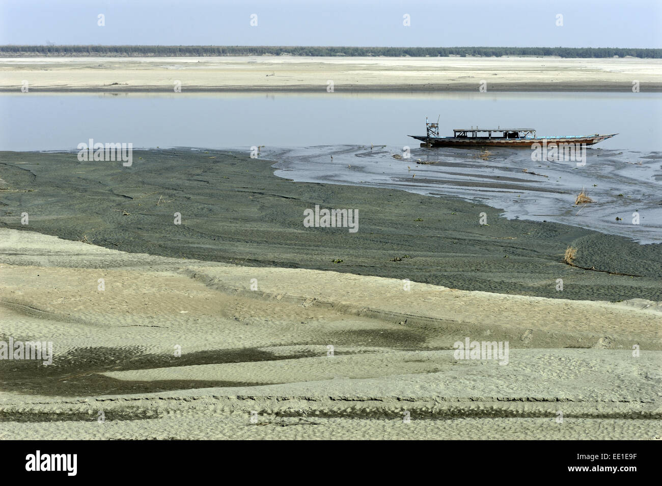 View of riverbank and river with low water levels, with stranded boat, River Brahmaputra, Kaziranga N.P., Assam, India, January Stock Photo