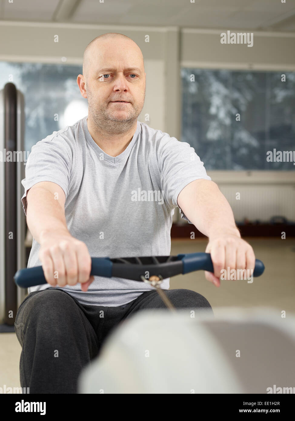 Mature man takes care of his health and he rowing in the gym Stock Photo