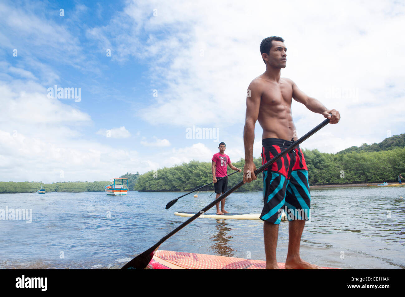 Locals riding stand-up surf boards, Caraiva River. Bahia, Brazil, South America Stock Photo