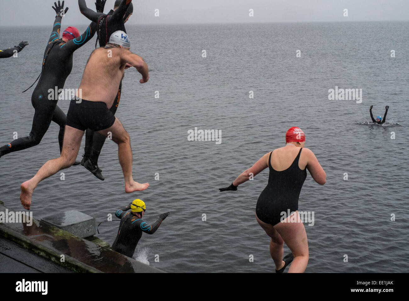 New Years Day swimmers take to the water from the pier at Luss in to the freezing waters of Loch Lomond, Scotland. Stock Photo