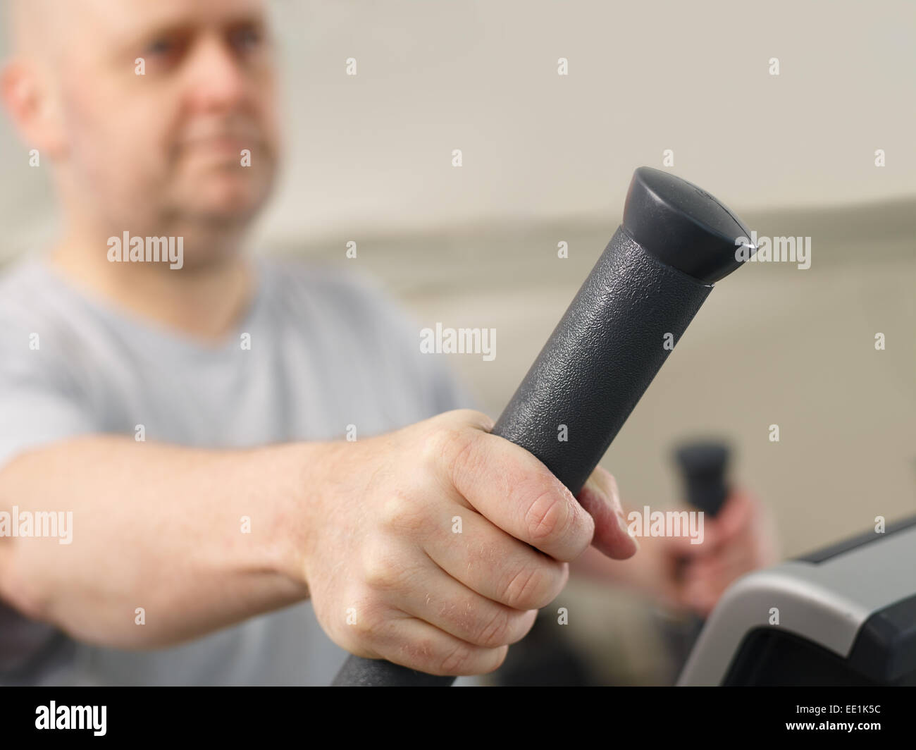 Close up, mature man takes care of his health and he use elliptical trainer in the gym - focus on a hand Stock Photo