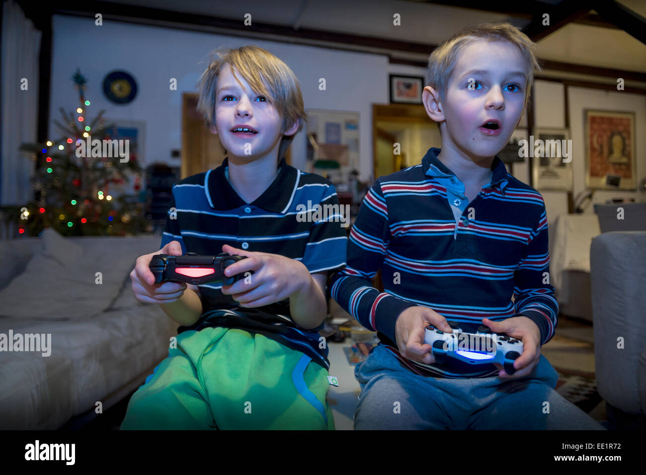 two young brothers sitting in front TV and playing video game Stock Photo