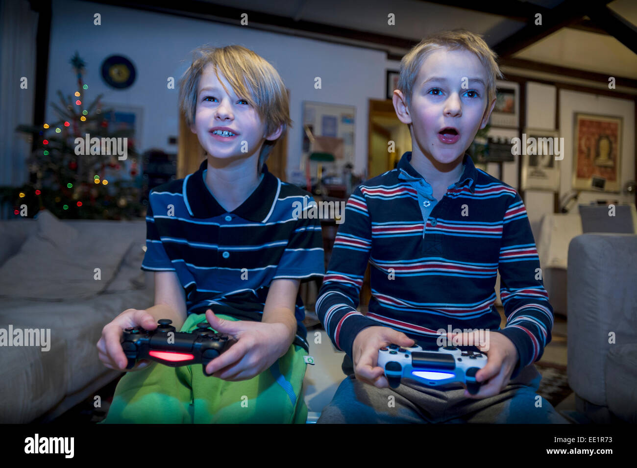 two young brothers sitting in front TV and playing video game Stock Photo