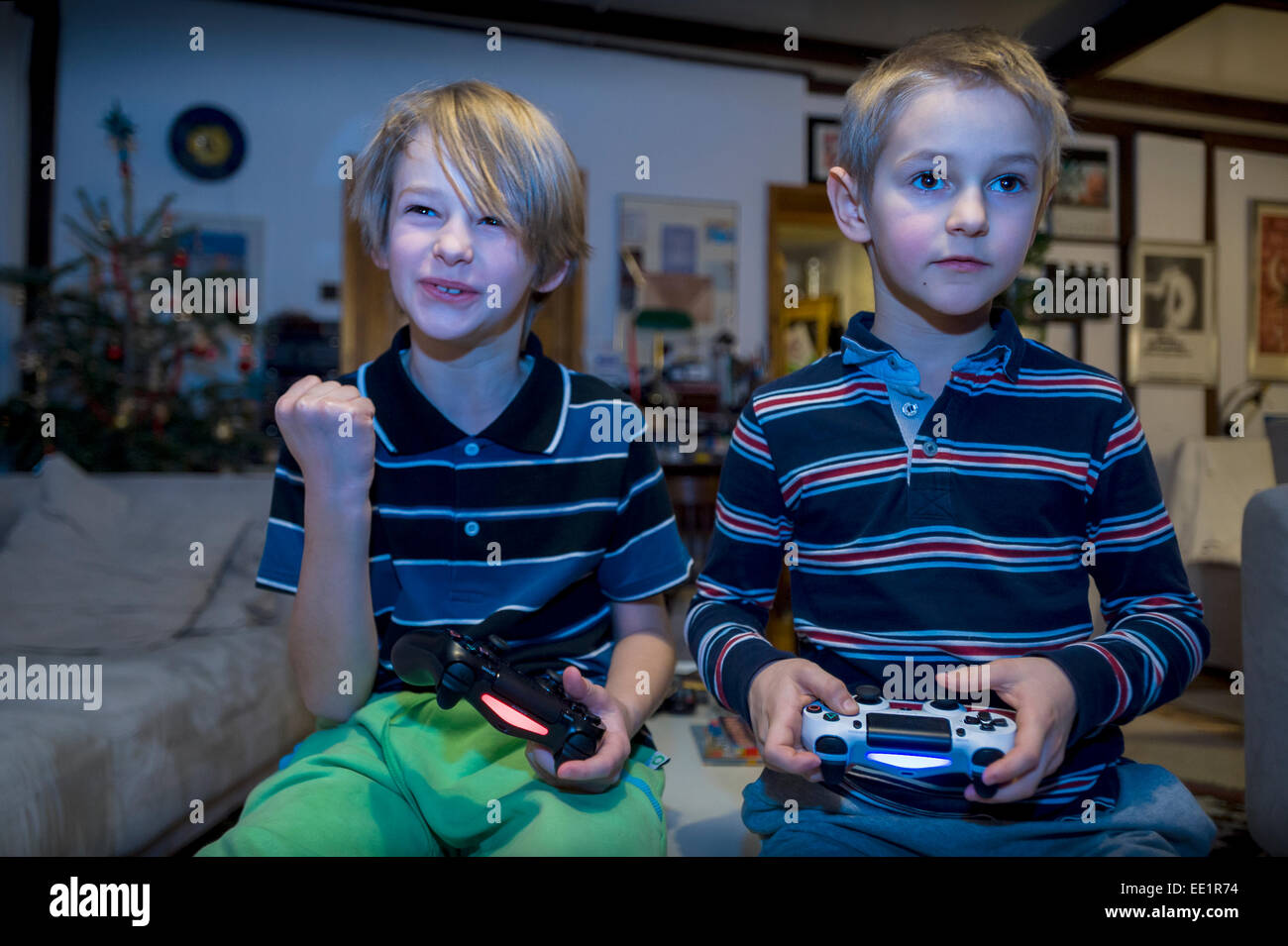 two young brothers sitting in front TV and playing video game Stock Photo