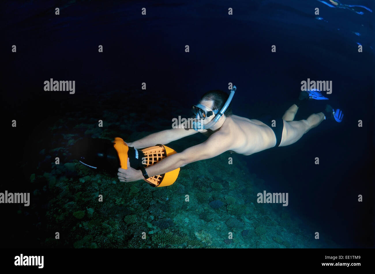 Freediver swims to underwater scooter, night diving in the Red Sea, Egypt Stock Photo