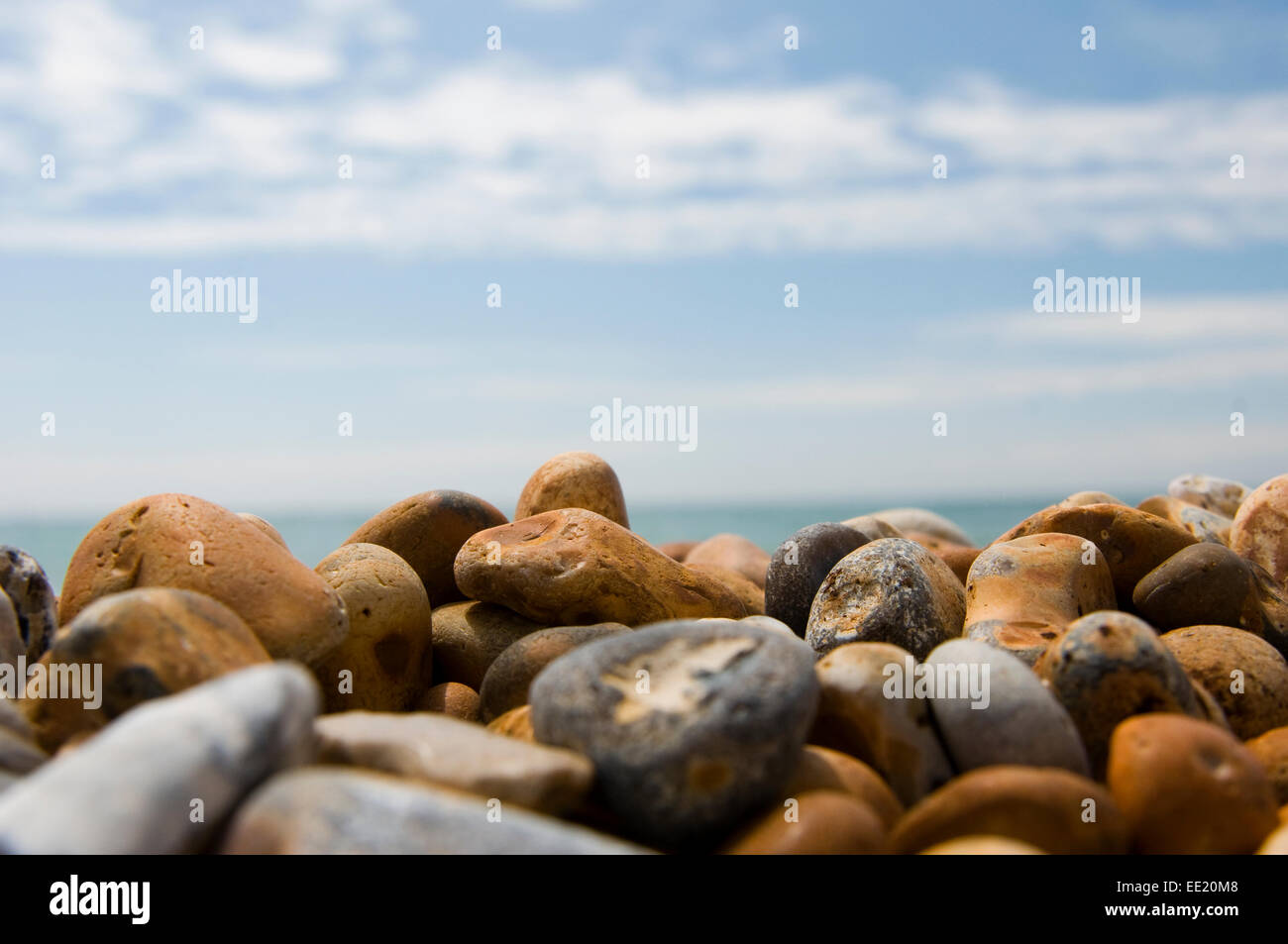 close up of pebbles on a beach with the sea and sky out of focus in the background Stock Photo