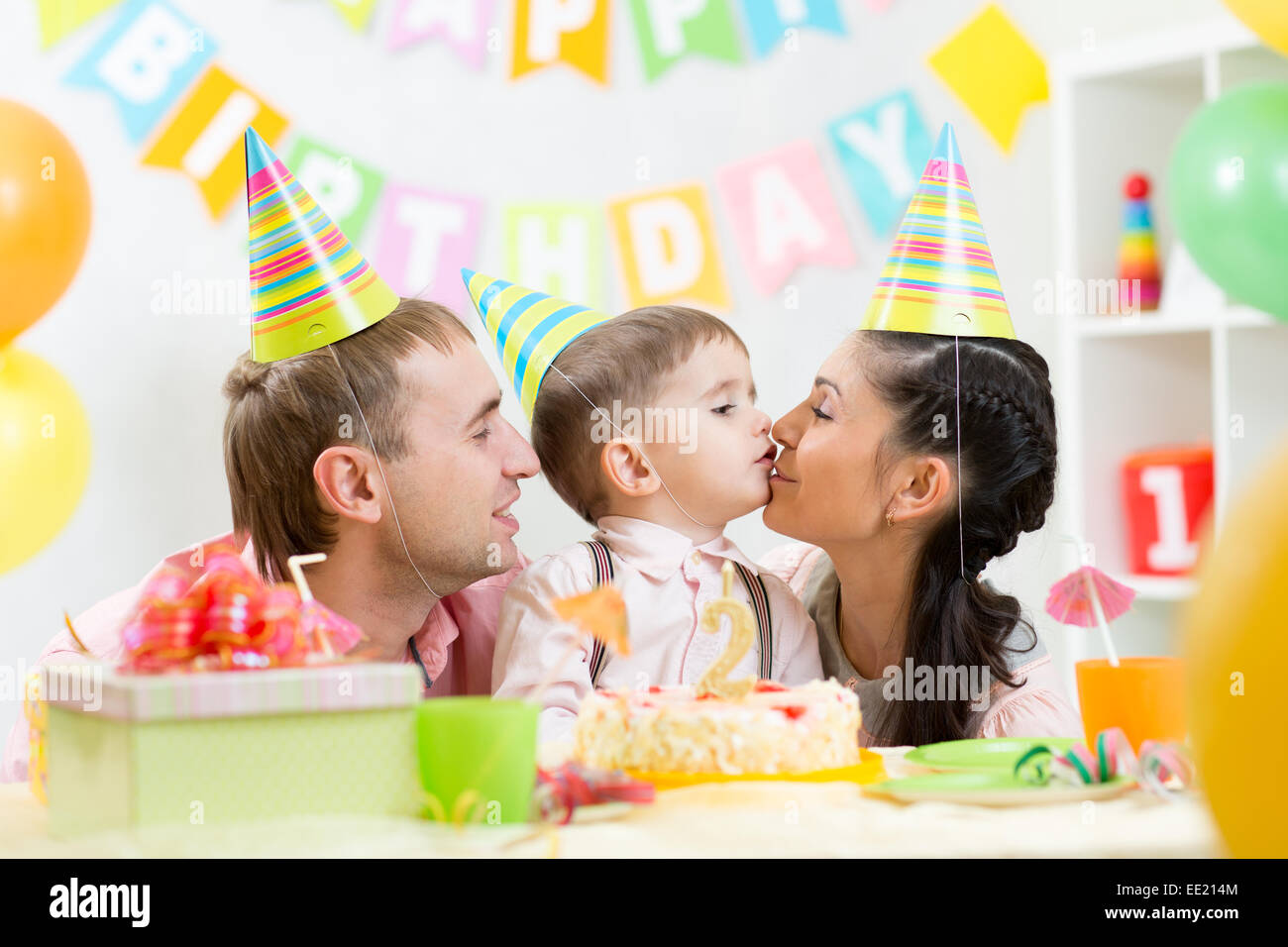 parents kiss their son celebrating child birthday Stock Photo