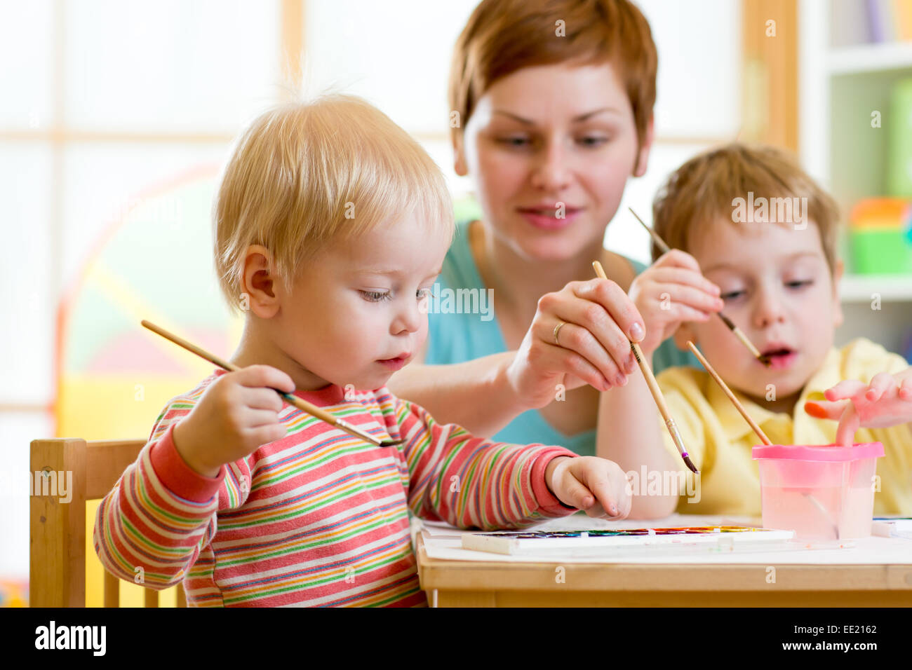 mother teaching her kids to paint Stock Photo