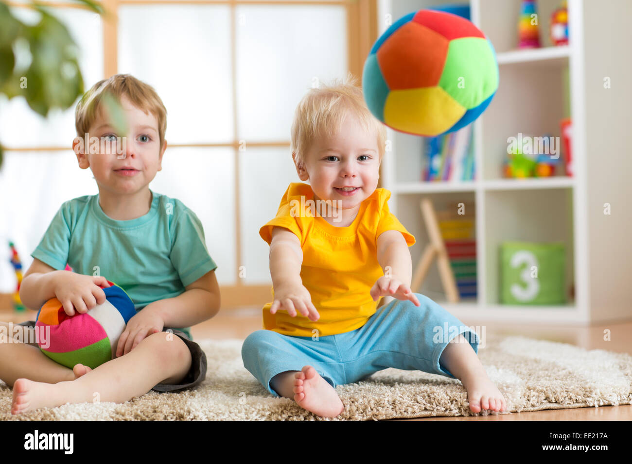 children playing with soft ball in playroom Stock Photo