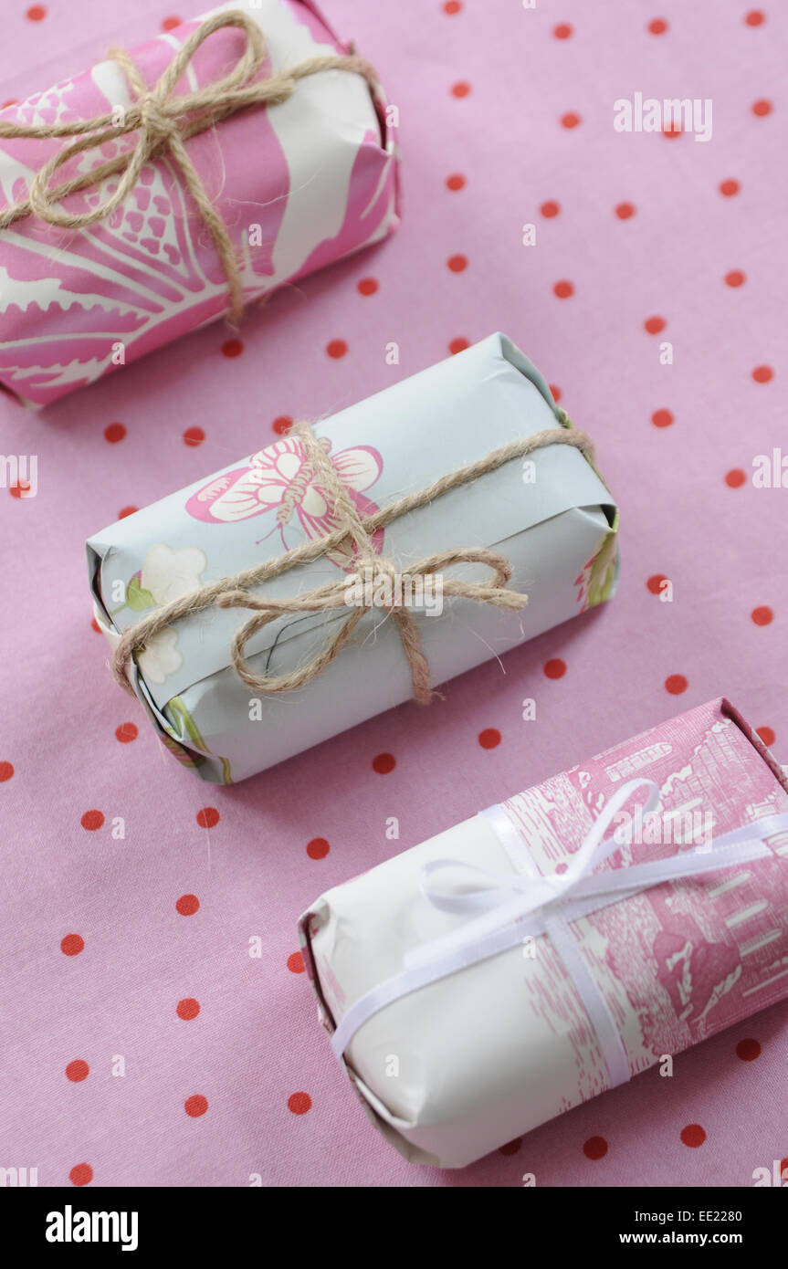 three pretty wrapped gifts on a pastel pink with red polka dot background Stock Photo
