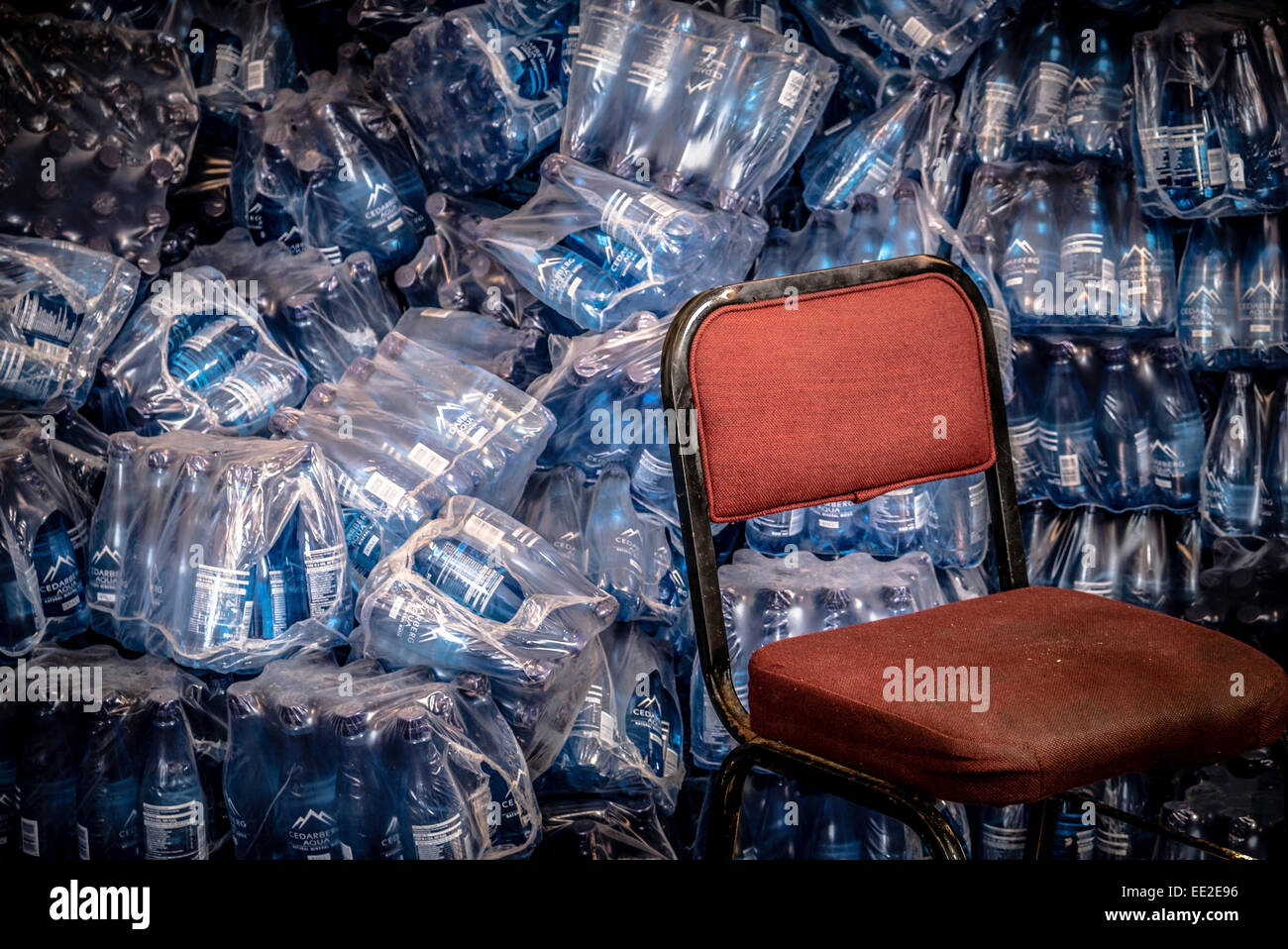 A red chair and and heap of water bottles in a storage area of the cafe on Robben Island, Cape Town, South Africa. Stock Photo