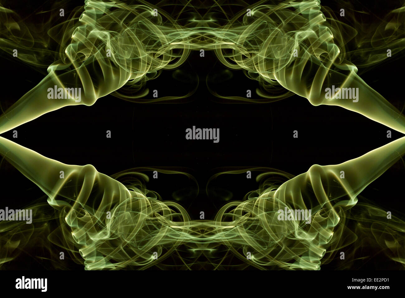 Reflected and mirrored symmetrical lime green smoke pattern against a black background. Stock Photo