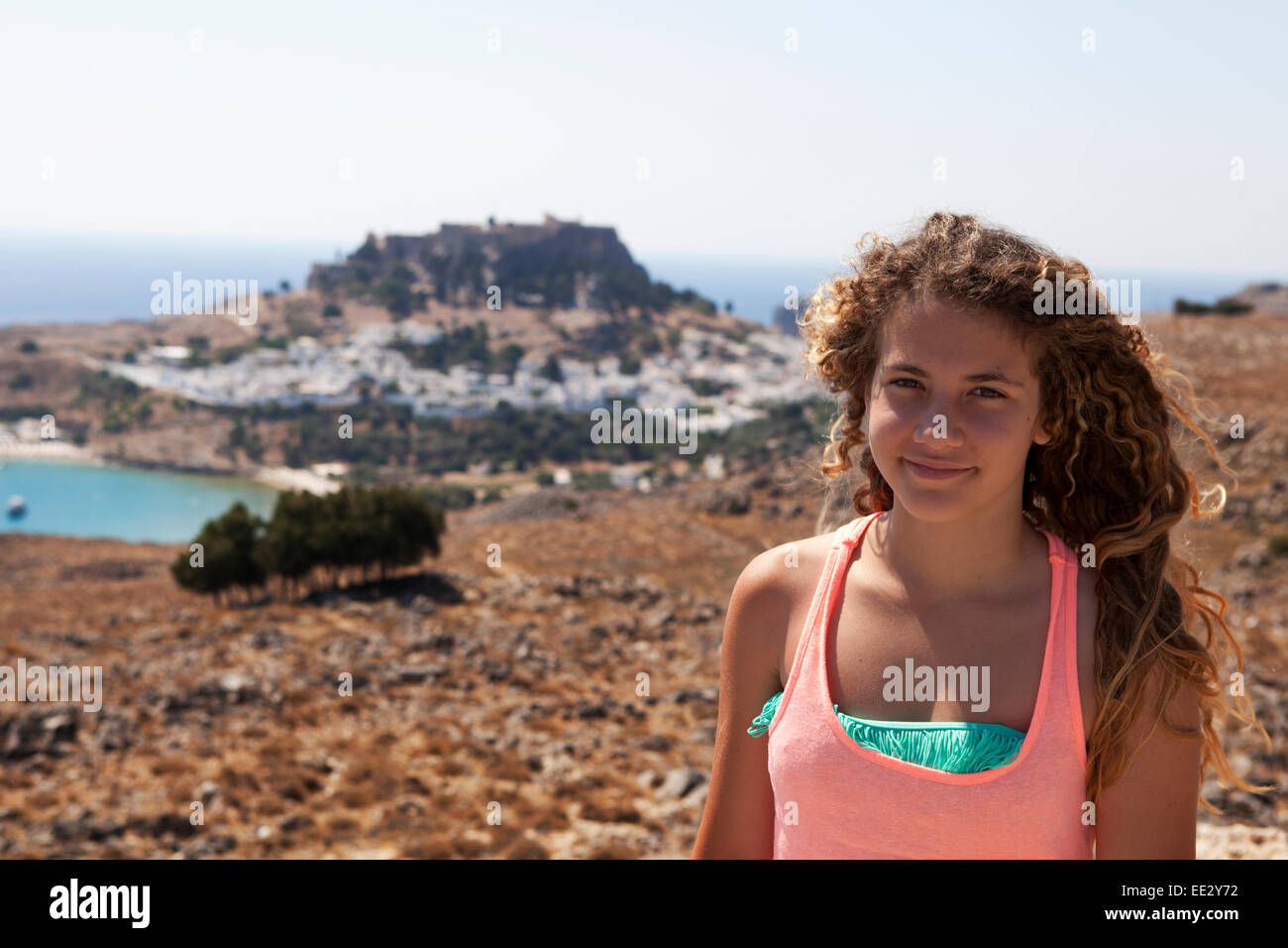 Young blond curly girl standing in front of a Greek view. Lindos, Rhodes island, Greece Stock Photo