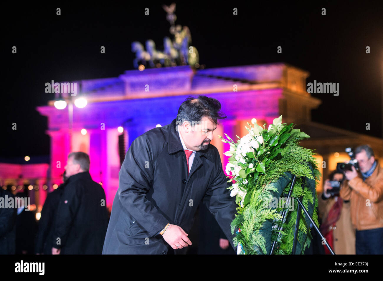 Berlin, Germany. 13th Jan, 2015. Chairman of the Central Committee of Muslims in Germany, Aiman Mazyek, straightens the ribbon on a wreath in front of the French Embassy during a vigil for the victims of the attacks in France at the Brandenburg Gate in Berlin, Germany, 13 January 2015. The Central Committee of Muslims and the Turkish community have invoked the slogan 'Stand together - Show face' for the rally against Islamist terror and for the peaceful co-existence of the religions. Photo: MAURIZIO GAMBARINI/dpa/Alamy Live News Stock Photo