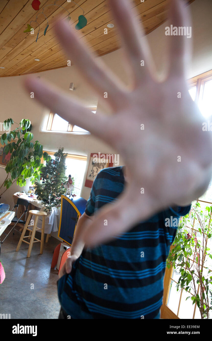Teenage boy putting hand in front of camera, not wanting to be photographed. Stock Photo