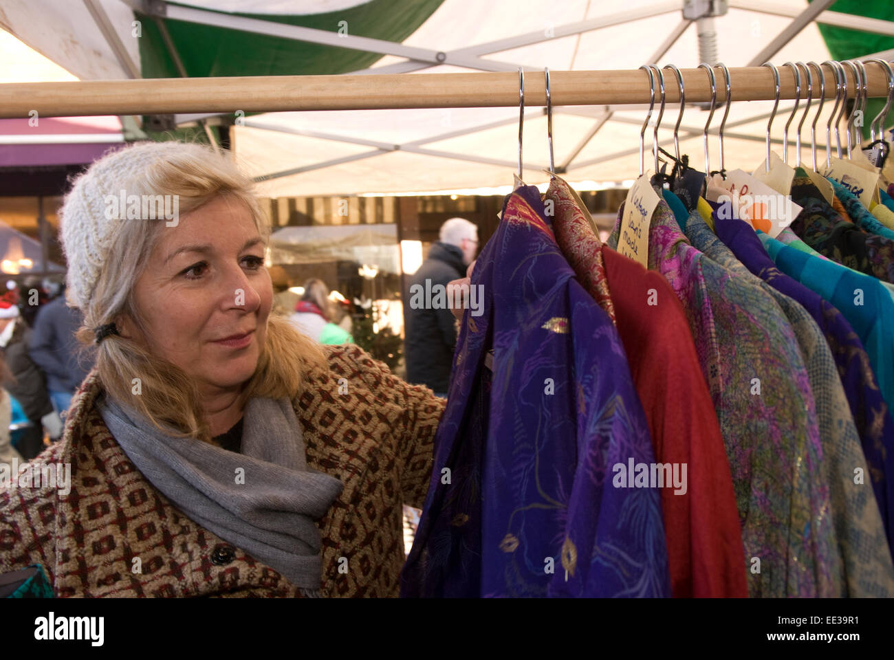 Woman perusing clothes stall at an outdoor christmas market, Haslemere, Surrey, UK. Stock Photo
