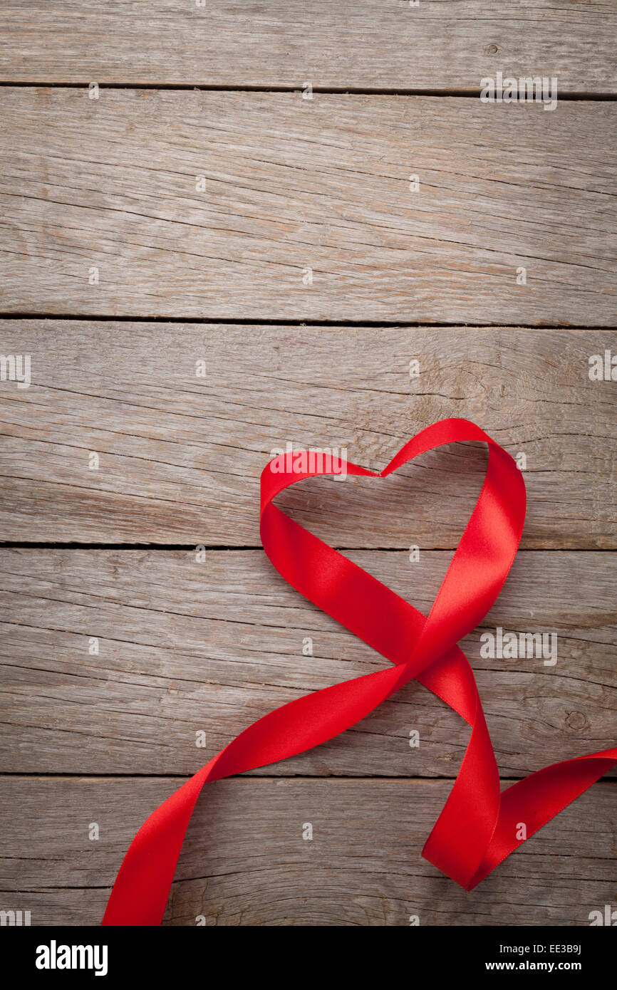 Valentines day heart shaped red ribbon over wooden table background ...