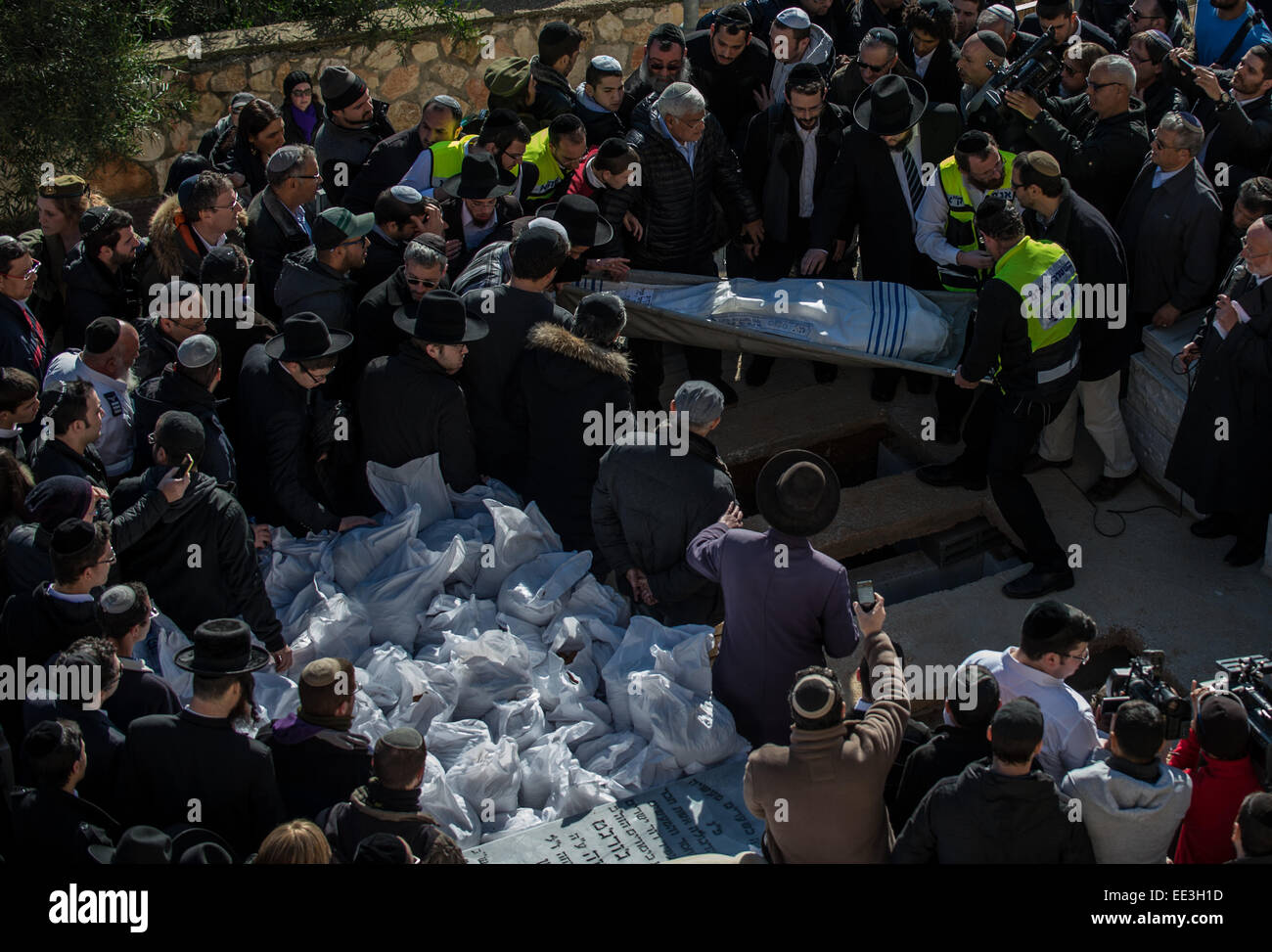 Jeruslaem, Israel. 13th Jan, 2015. A body of victim of Paris supermarket attack is carried to the grave during a funeral ceremony at Givat Shaul cemetery, on the outskirts of Jerusalem, on Jan. 13, 2015. Israeli leaders and multitude of mourners gathered Tuesday with the families of four Jewish victims of last week's terror attack on a Paris kosher supermarket for a solemn funeral ceremony at a Jerusalem cemetery. Yoav Hattab, Yohan Cohen, Philippe Braham and Francois-Michel Saada, were gunned down on Friday during a hostage attack in Paris.market in eastern Paris. Credit:  Xinhua/Alamy Live N Stock Photo