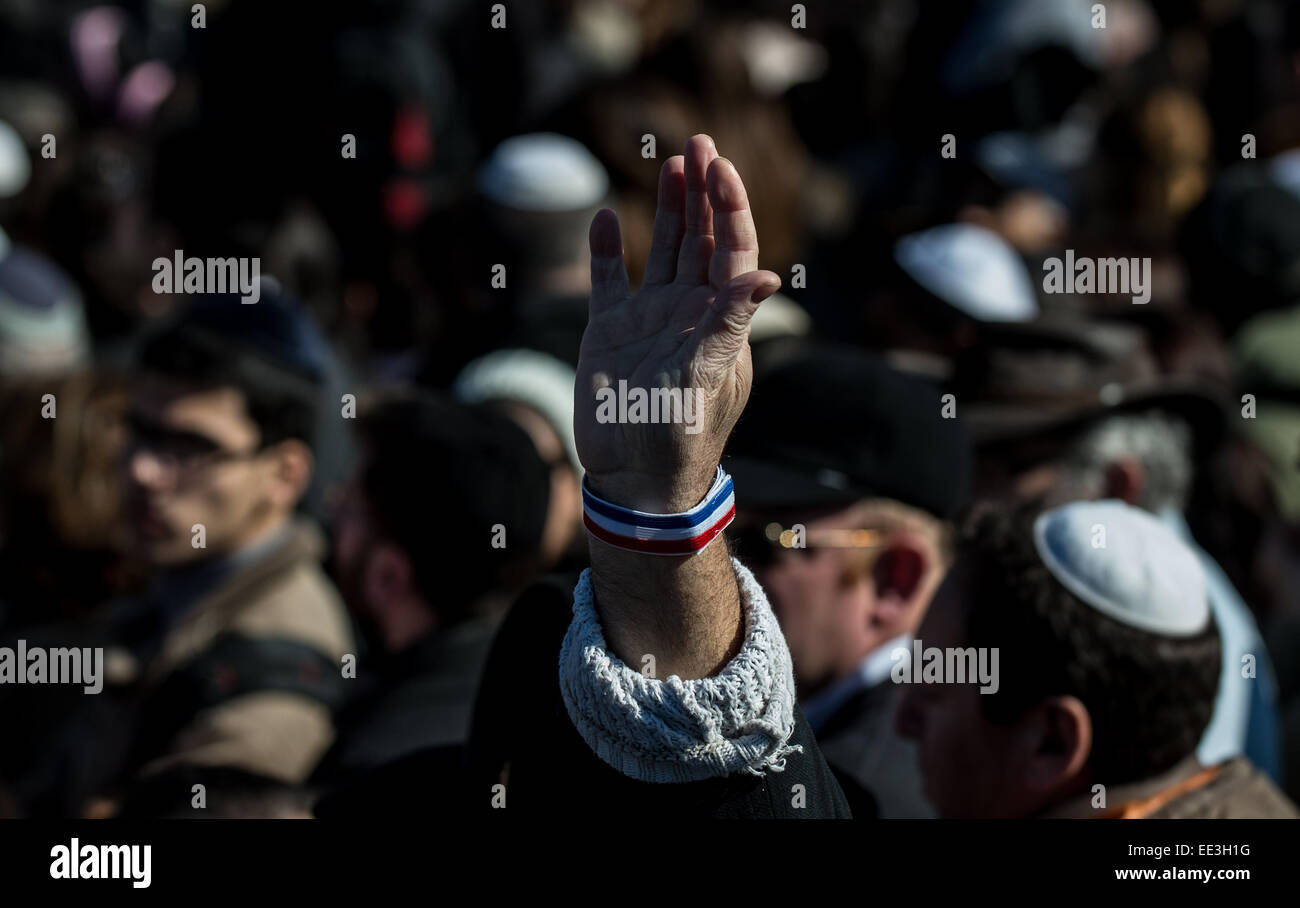 Jeruslaem, Israel. 13th Jan, 2015. A man raises his hand with a band of French national flag on his wrist during a funeral ceremony for the four victims of Paris supermarket attack at Givat Shaul cemetery, on the outskirts of Jerusalem, on Jan. 13, 2015. Israeli leaders and multitude of mourners gathered Tuesday with the families of four Jewish victims of last week's terror attack on a Paris kosher supermarket for a solemn funeral ceremony at a Jerusalem cemetery. Yoav Hattab, Yohan Cohen, Philippe Braham and Francois-Michel Saada, were gunned down on Friday during a hostage atta © Xinhua/Alam Stock Photo