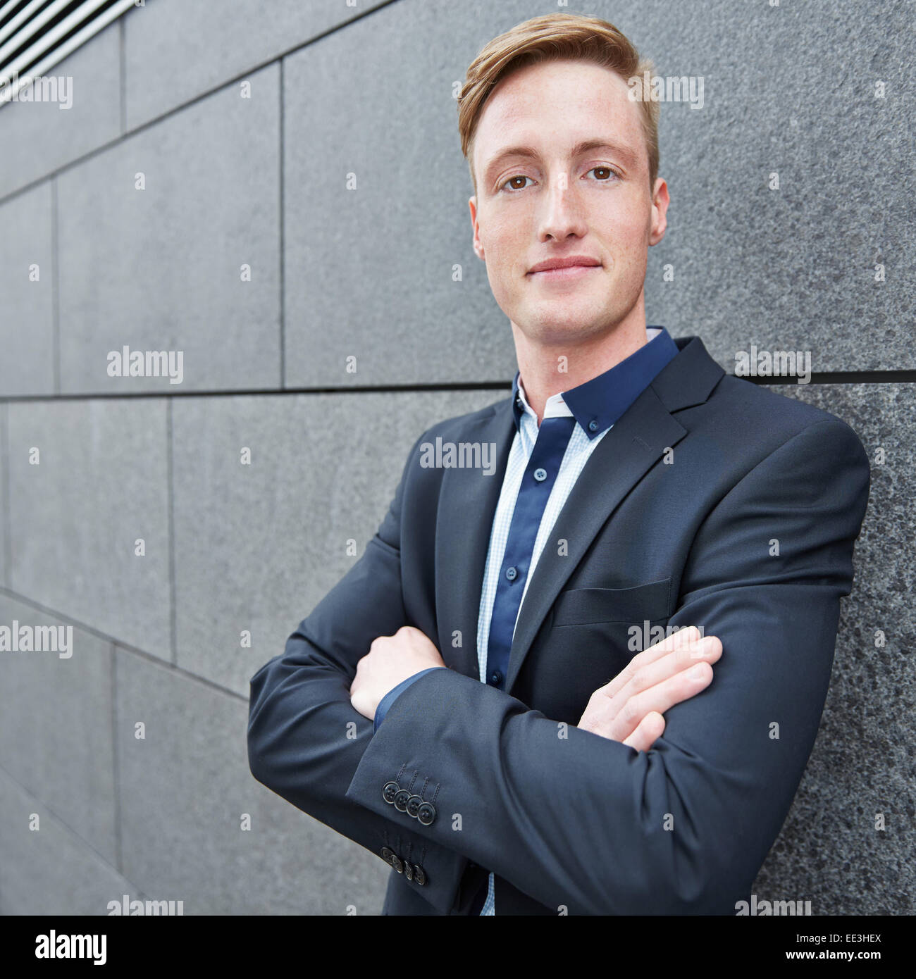 Smiling business man with his arms crossed leaning on a wall Stock ...