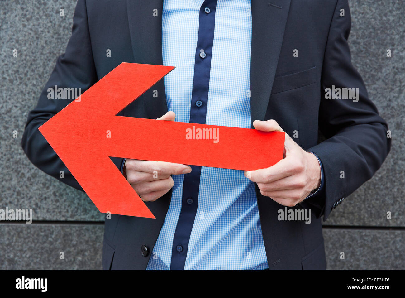 Business man holding big red arrow to the left Stock Photo - Alamy