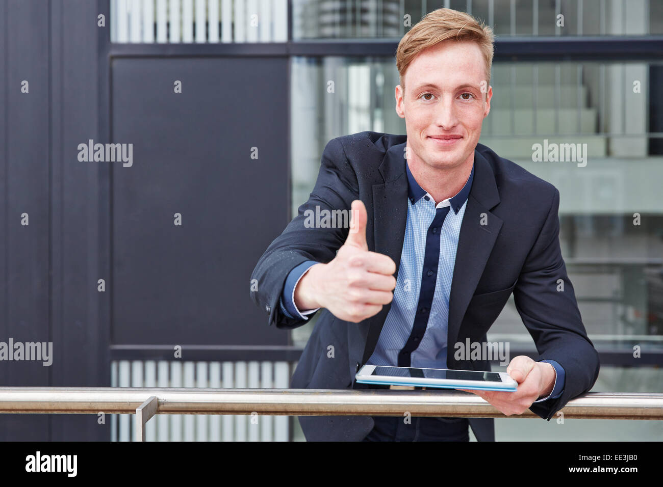 Smiling young business man with tablet computer holding his thumbs up Stock Photo