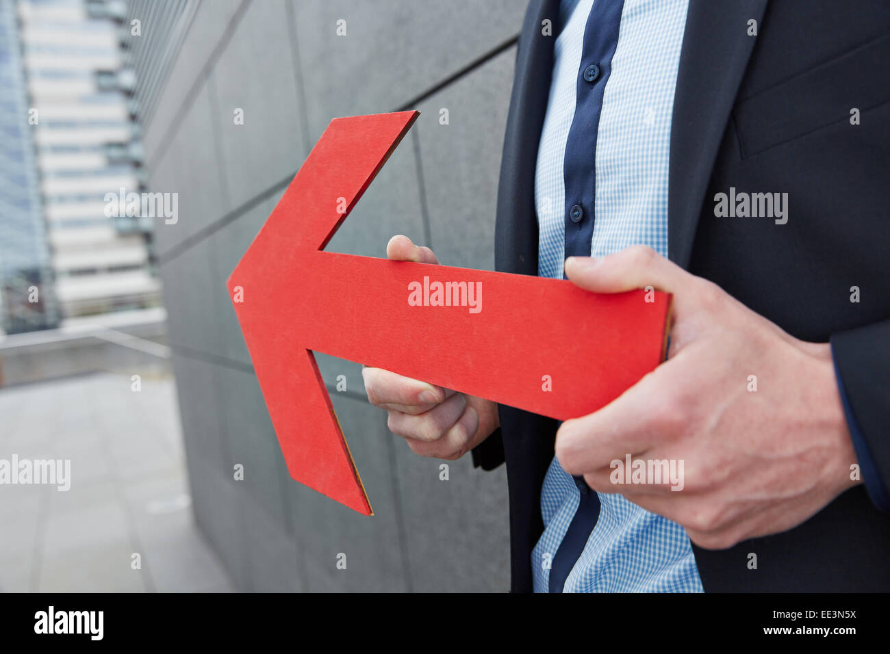 Business man holding red arrow to the left in the city Stock Photo - Alamy