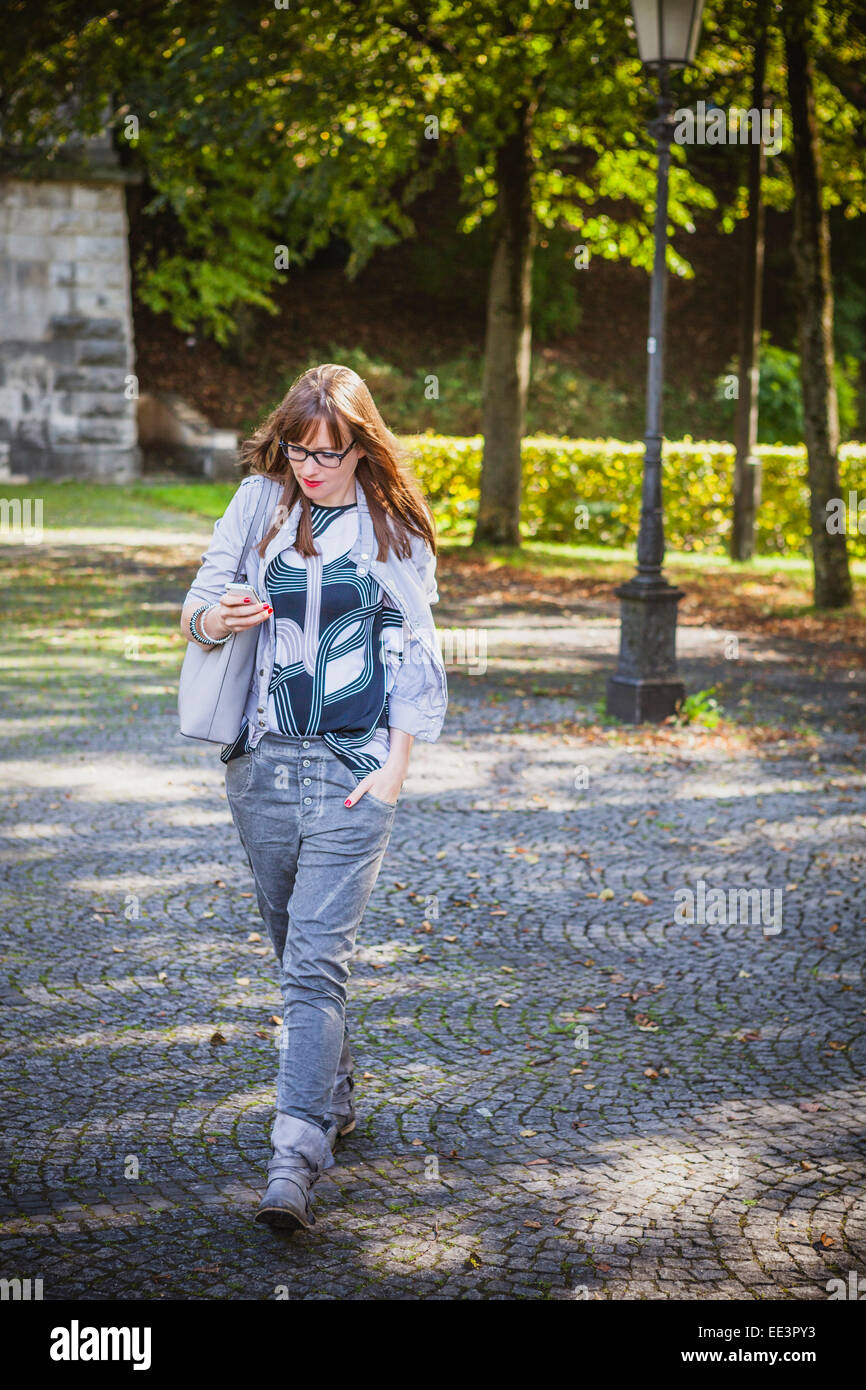 Young woman text messaging outdoors, Munich, Bavaria, Germany Stock Photo
