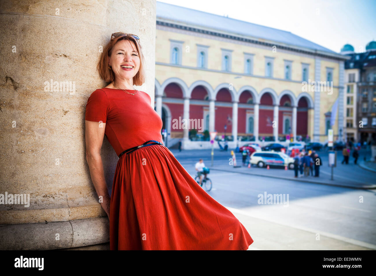 Senior woman leans against pillar smiling happily, Munich, Bavaria, Germany Stock Photo
