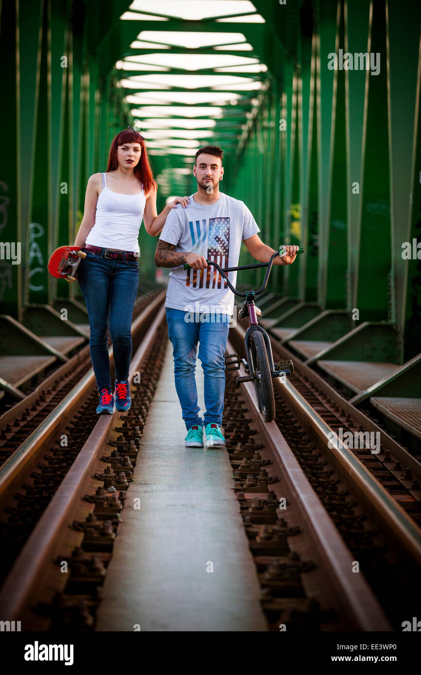 Young couple with BMX bicycle walking over bridge Stock Photo