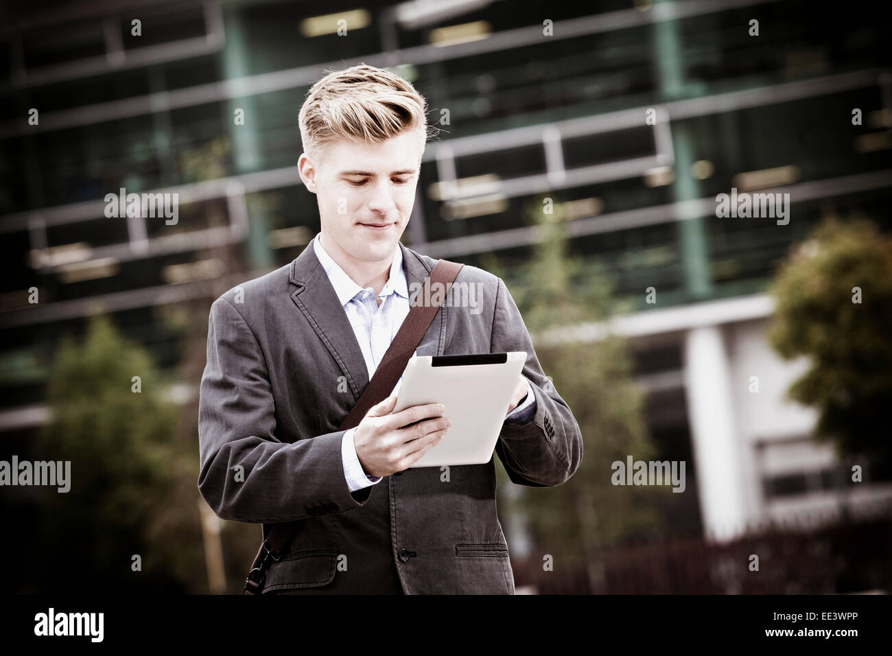 Young businessman using digital tablet outdoors, Munich, Bavaria, Germany Stock Photo