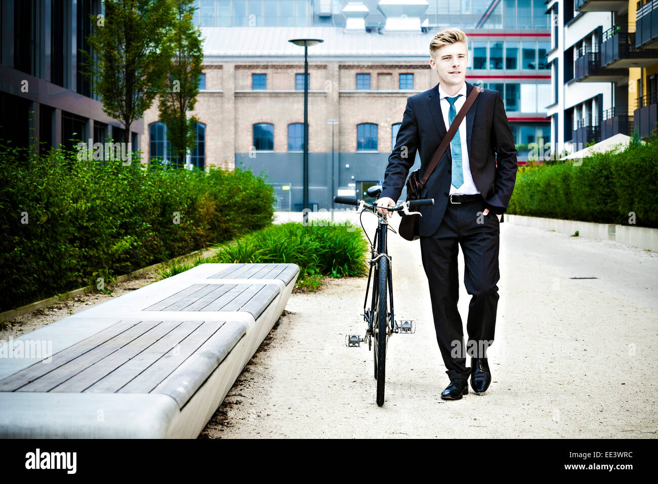 Young businessman riding bicycle, Munich, Bavaria, Germany Stock Photo