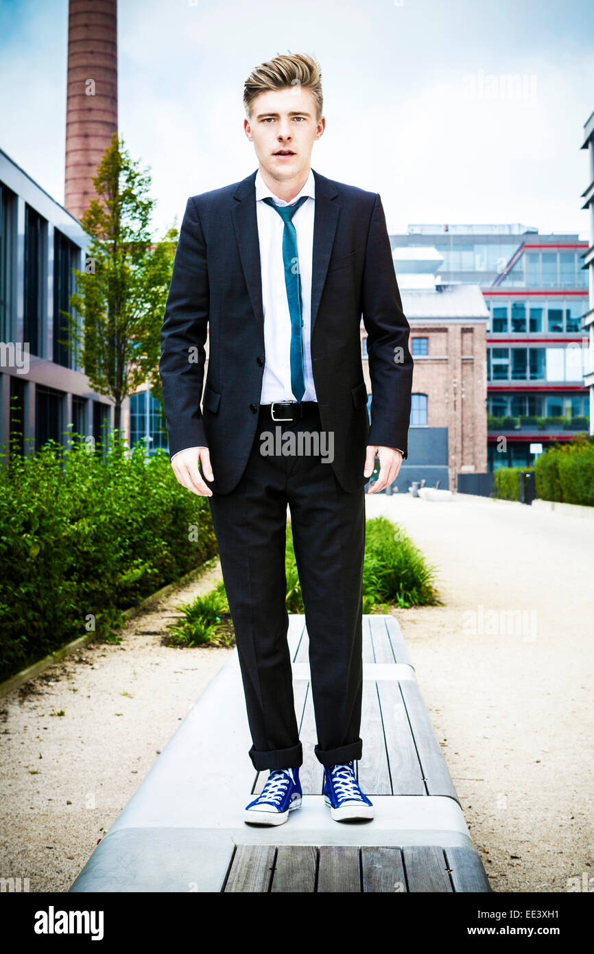 Young businessman against office building, Munich, Bavaria, Germany Stock Photo