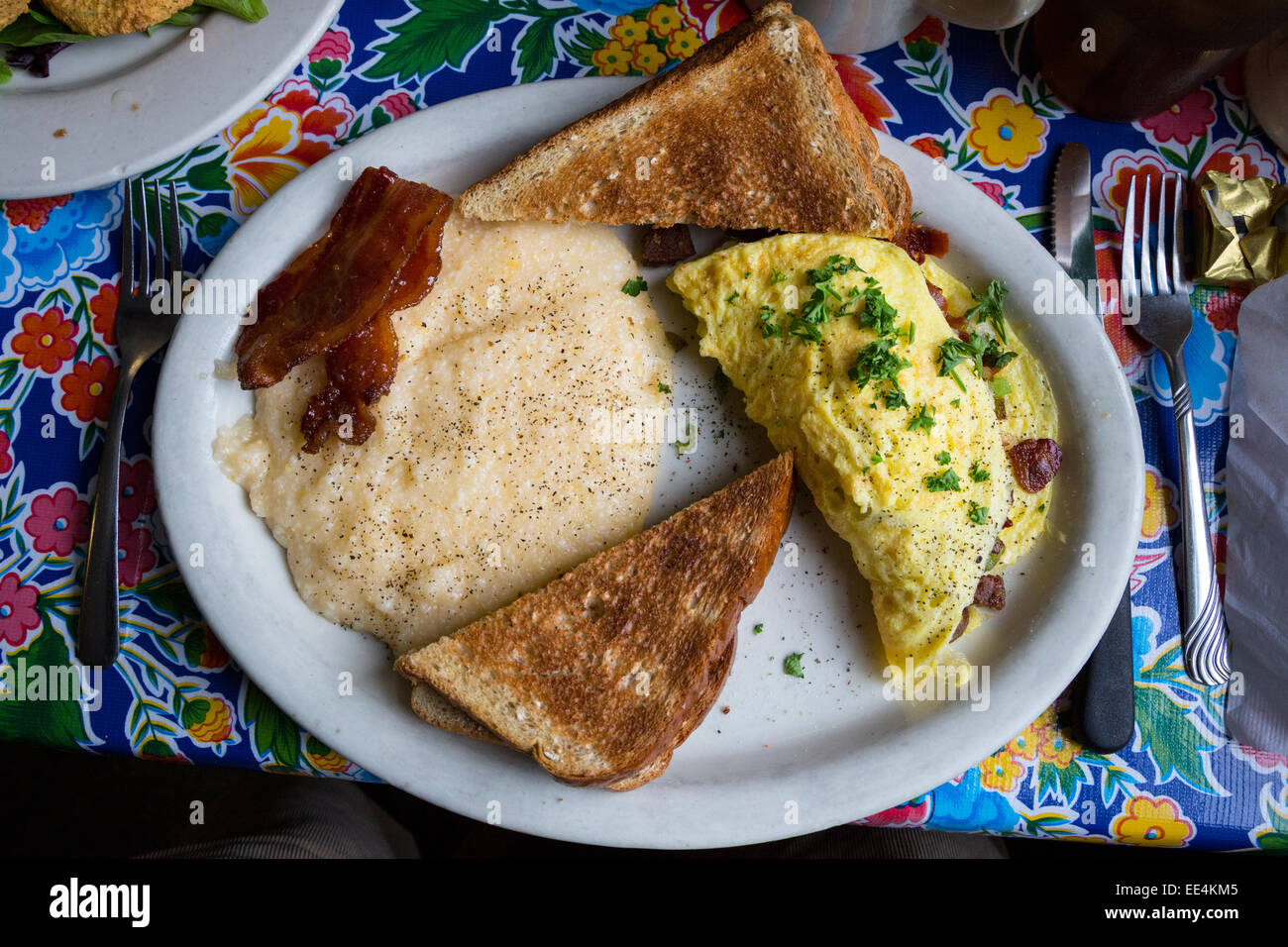 New Orleans, Louisiana.  Bacon and Sausage Omelet, Praline Bacon, Toast, Grits. Breakfast at Elizabeth's Restaurant, Bywater. Stock Photo