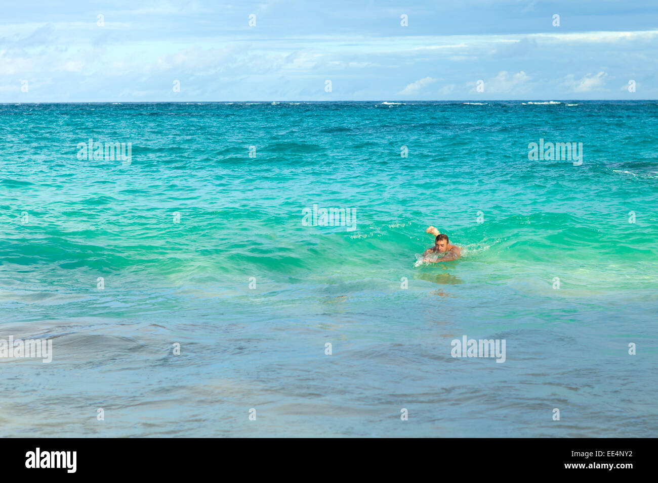 Man swimming alone in the waves body surfing at Bermudas John Smiths Bay beach. Stock Photo