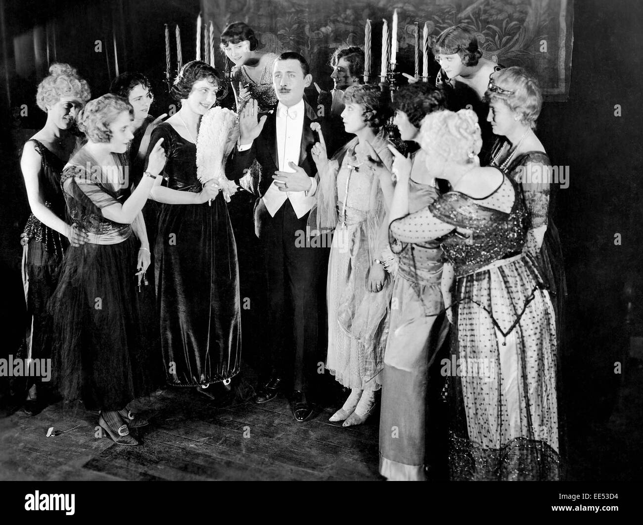 Lew Cody Surrounded by Group of Women, on-set of the Silent Film, 'The Beloved Cheater' (aka The Pleasant Devil), 1919 Stock Photo