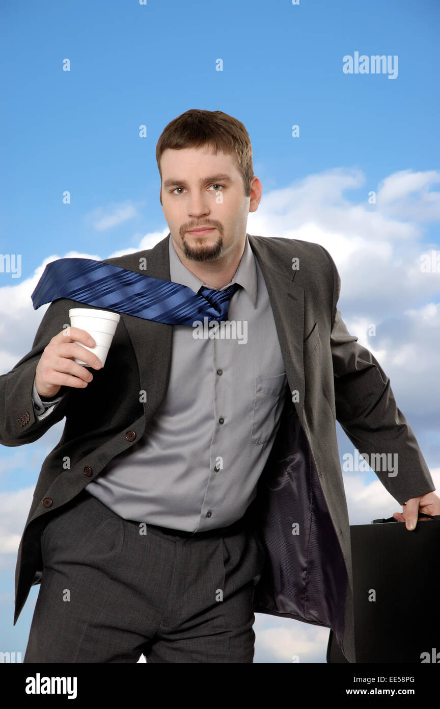 Businessman running with coffee and briefcase with serious expression.  He looks determined and focused. Stock Photo