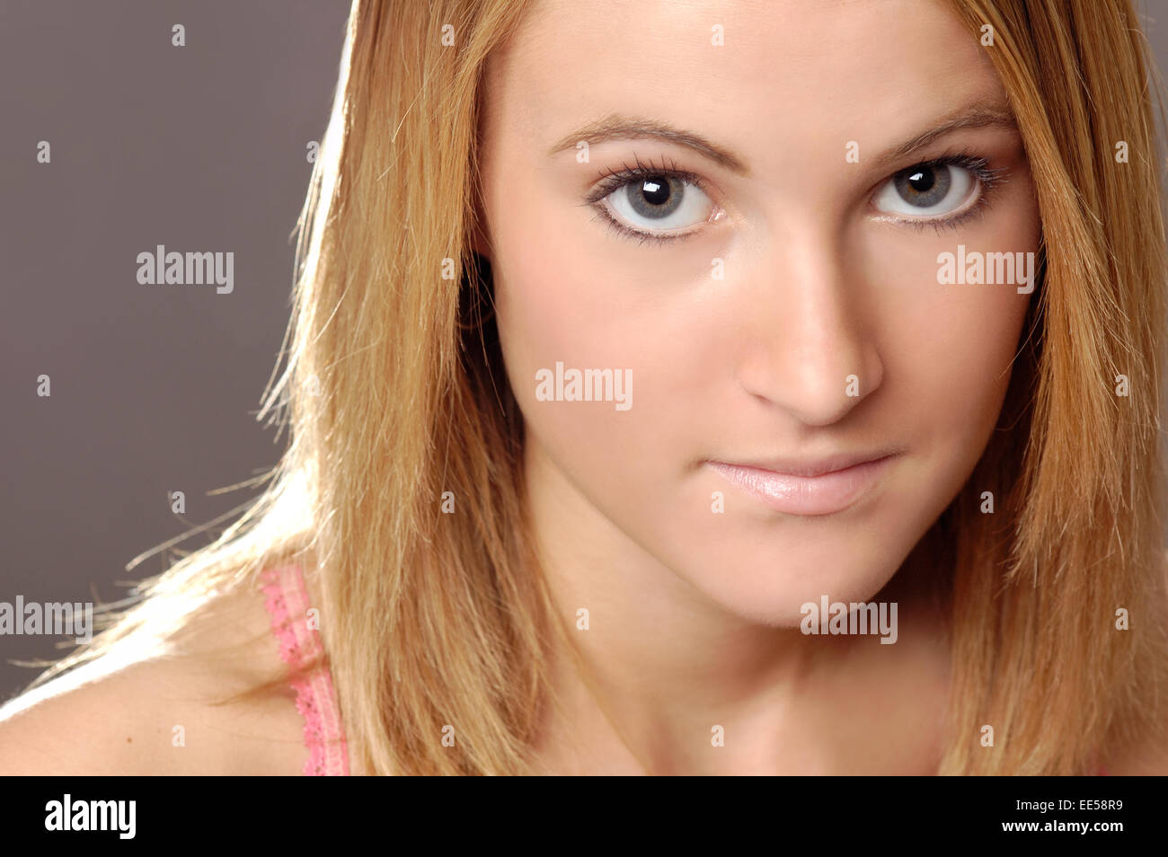 This stock photo shows a young woman with clear skin and natural looking make-up. She is making eye contact with the viewer Stock Photo