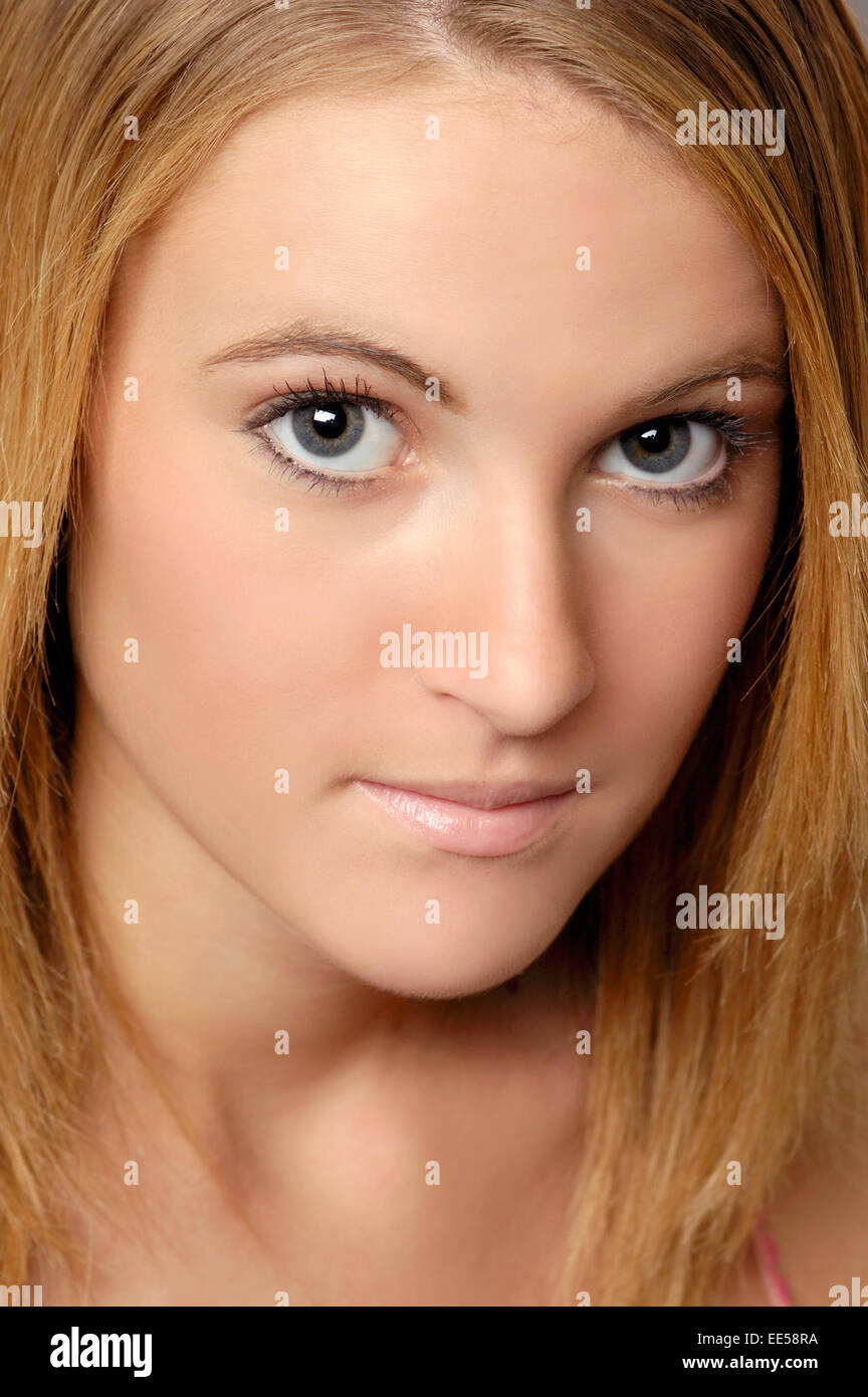 Close up view of a young woman's face. She has clear skin and is making eye contact. Stock Photo