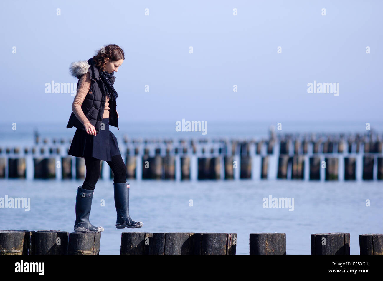 Taken from a beach near Rostock, a town in northern Germany. North Sea with a woman walking upon wooden sea defenses. Stock Photo