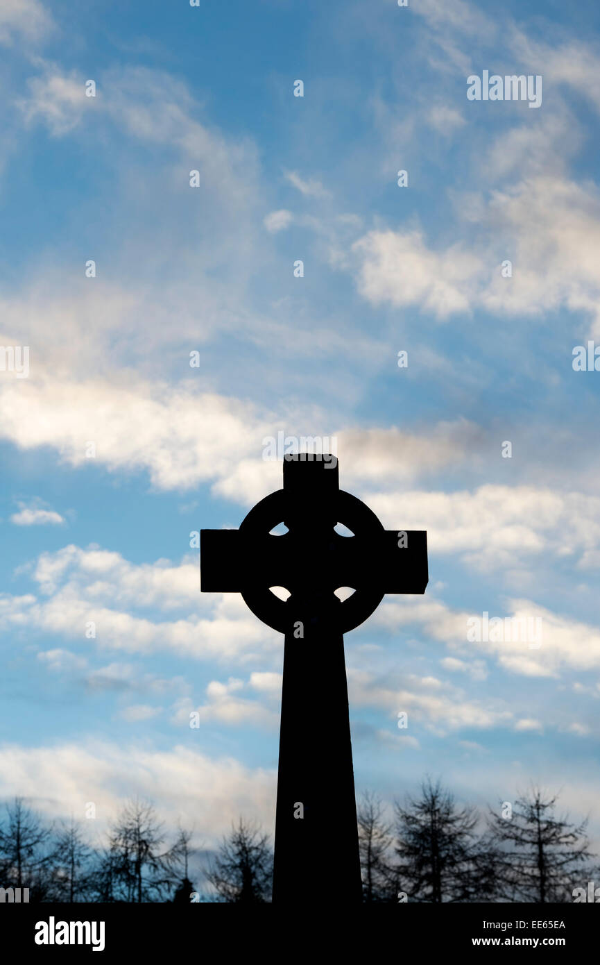 Stone celtic cross against blue sky in the early morning. Silhouette Stock Photo
