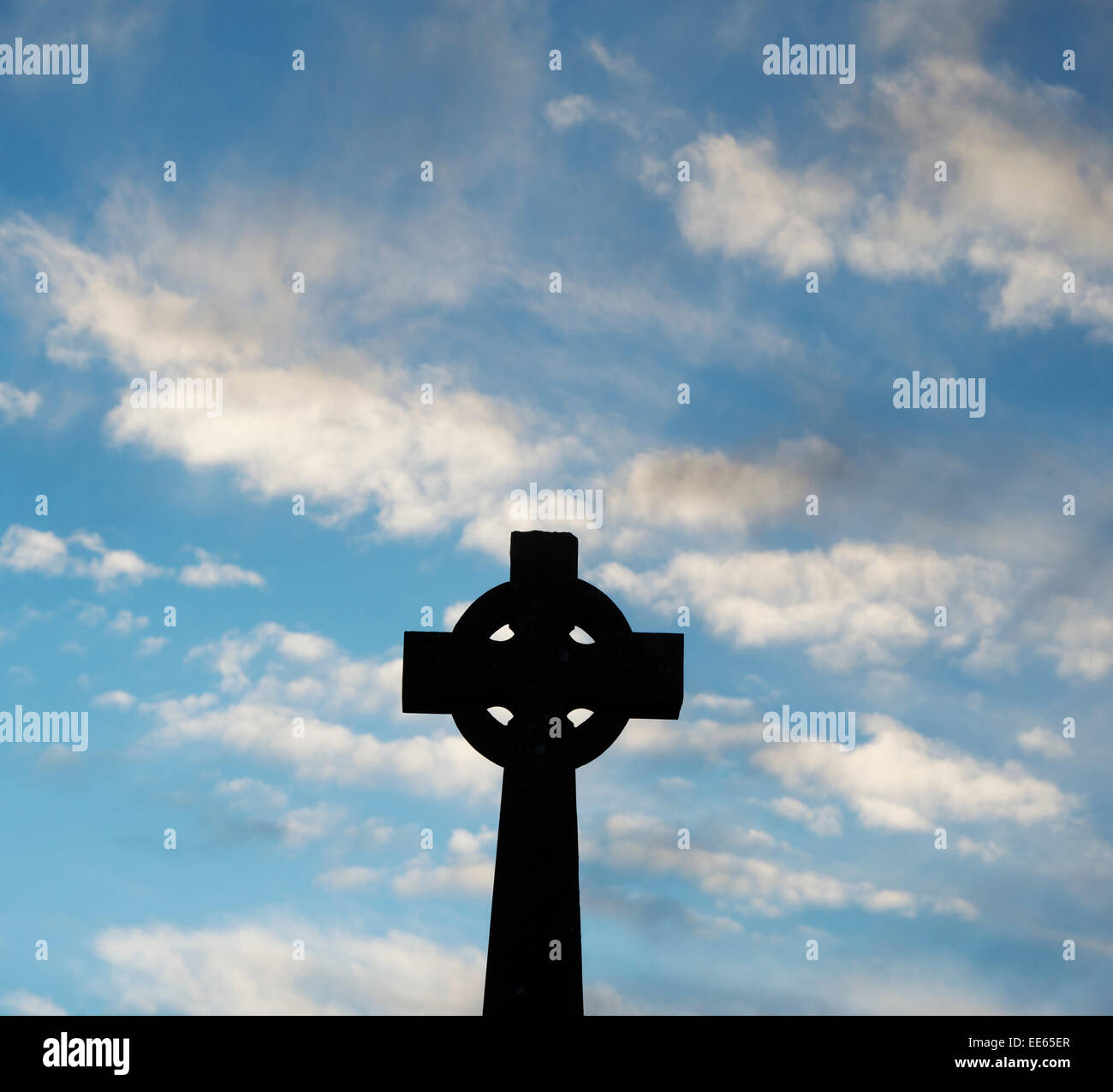 Stone celtic cross against blue sky in the early morning. Silhouette Stock Photo