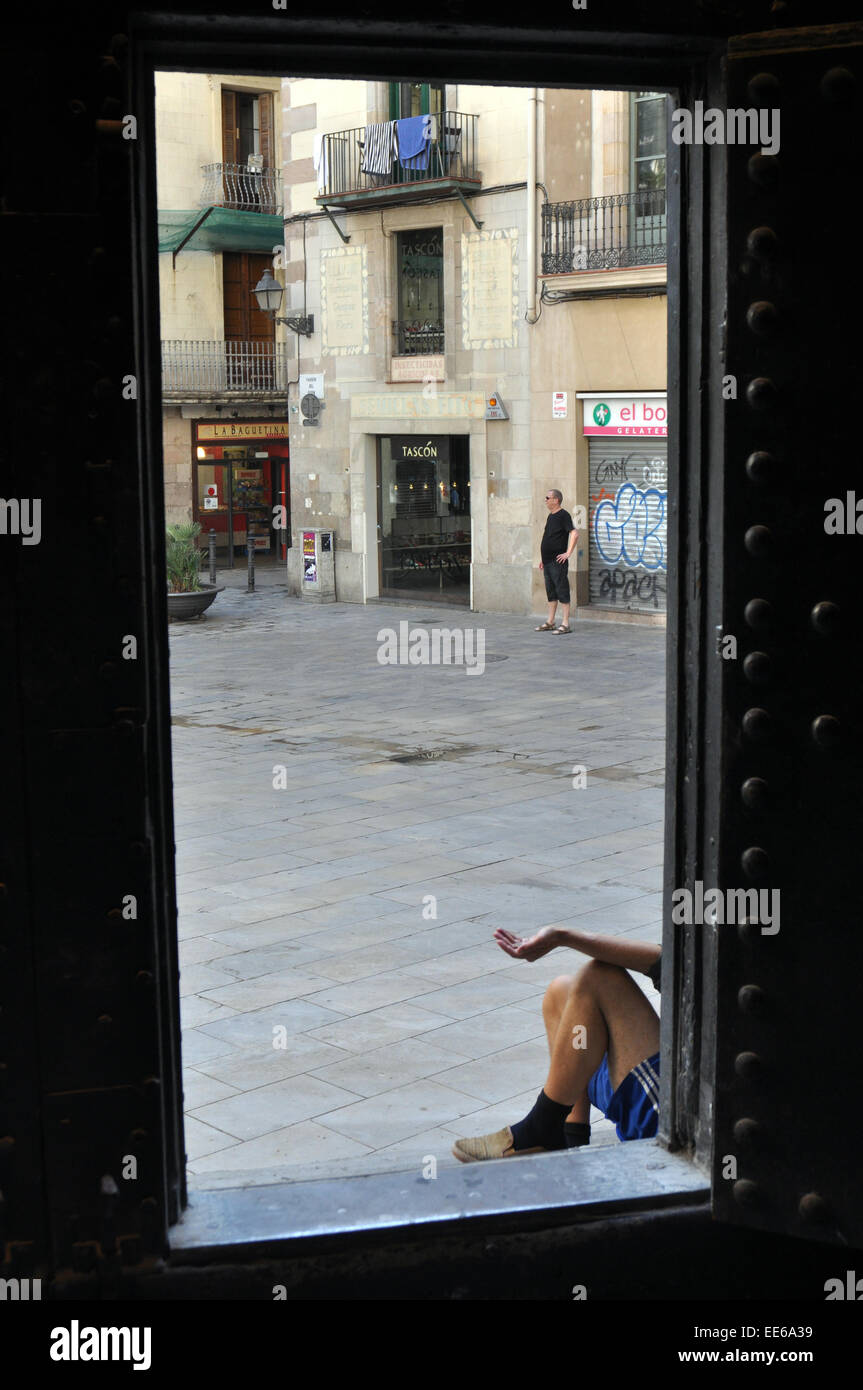 A beggar sits in the door way of a church, Barcelona. Basílica de la Mercé Spain Stock Photo