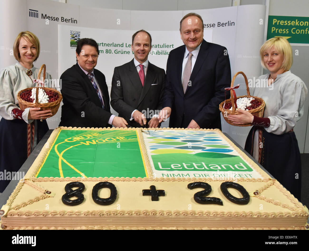 Christoph Minhoff (manager of the umbrella association of the food industry, L-R), Christian Goeke (manager of Messe Berlin) and Joachim Rukwied (President of the German Farmers' Association) cut a birthday cake together with Latvian hostesses before the beginning of the opening press conference of the 80th Green Week in Berlin, Germany, 14 January 2015. More than 1,600 exhibitors present their products in 26 hall complexes under the Funkturm Berlin from 16 until 25 January 2015. Latvia is this year's partner country. PHOTO: BERND SETTNIK/dpa Stock Photo