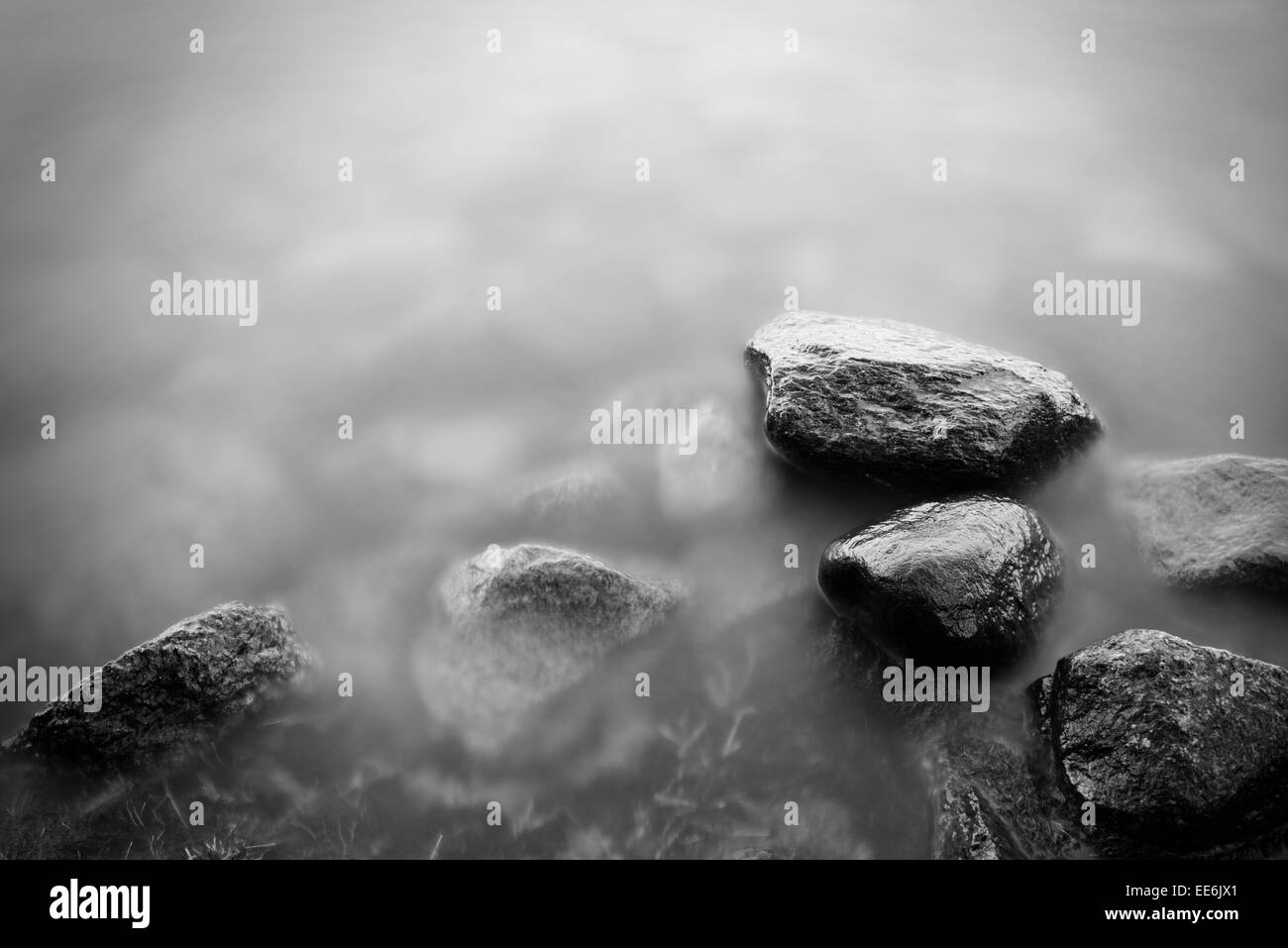 Tranquil nature scene with long exposure of dark rocks and still water