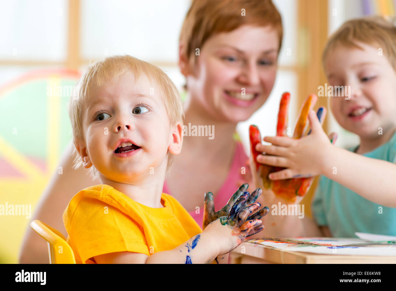 Cute woman playing and painting with children Stock Photo