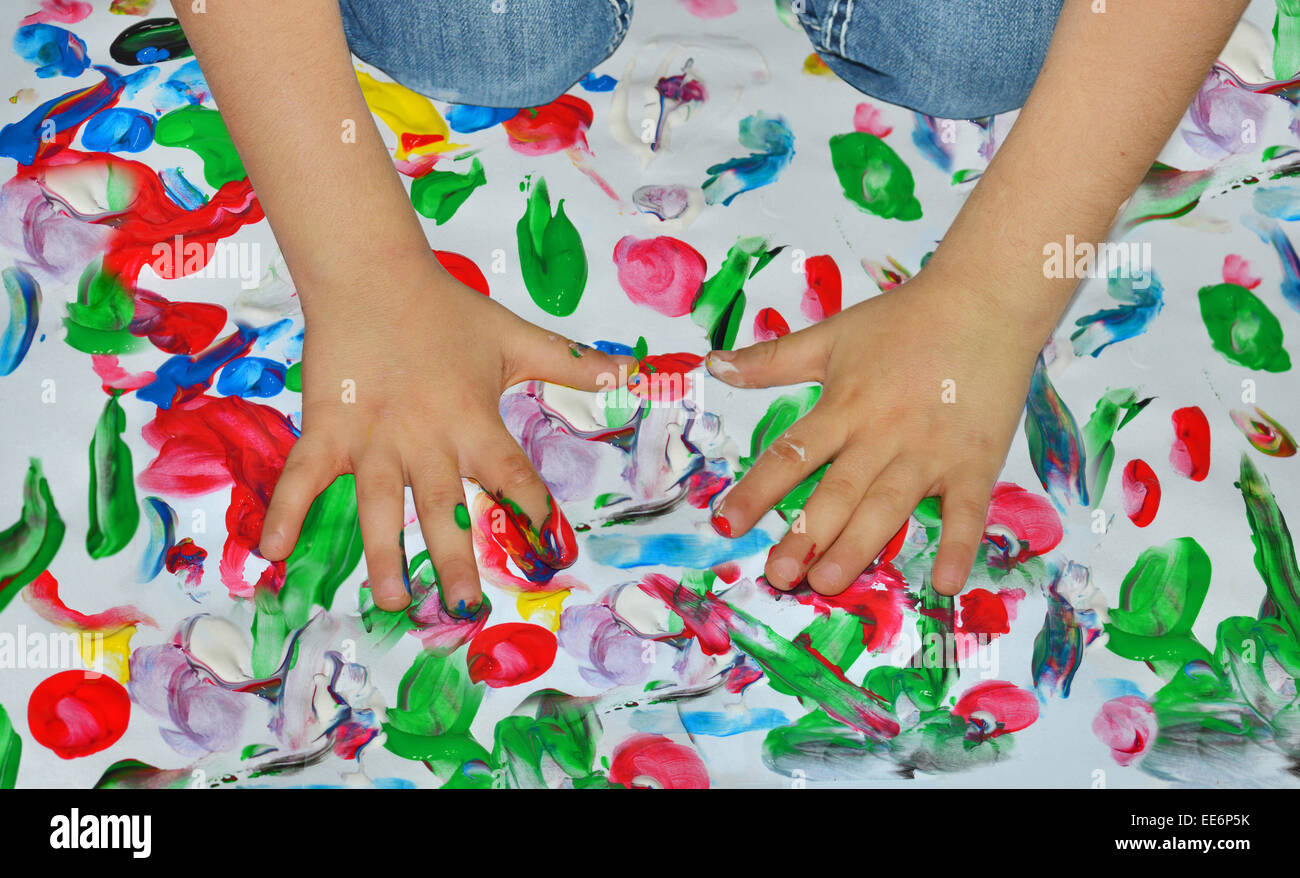 Kid paints with her fingers with different color paint Stock Photo