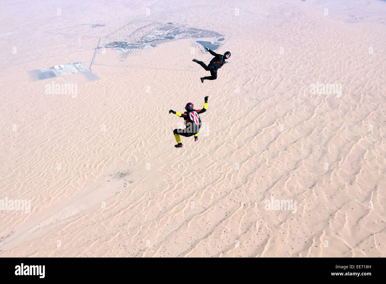 Two skydivers are training the sit fly position over a big desert area. Wondering where they are going to land afterwards? Stock Photo
